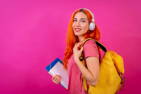 Redhead woman in studio photography dancing college student on a pink background, back to school