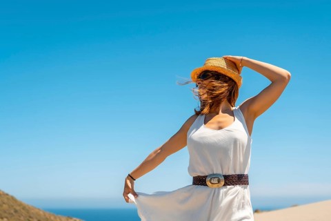 Cute woman holding her hat in a windy beach day in Cabo de Gata, Spain, Europe