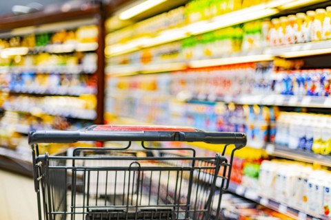 A shopping cart by a store shelf in a supermarket