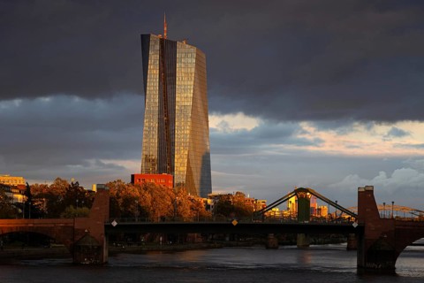 Dark clouds pass over the European Central Bank (ECB), illuminated by the last sunlight of the day,