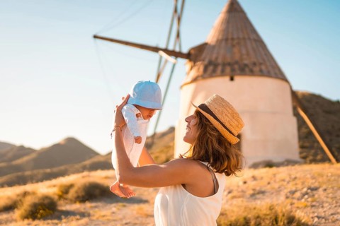 Mother raising a baby in arms next to a windmill in Cabo de Gata, Spain, Europe