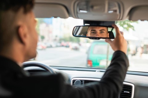 Young business man arranging his rear view mirror