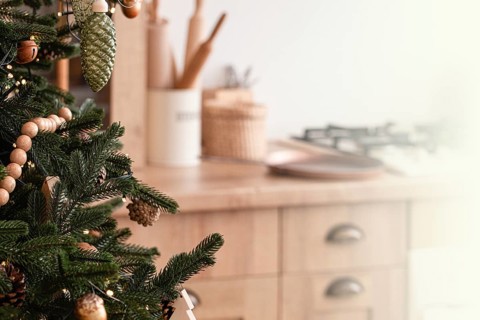 Close-up of decorated with wooden toys and garland big beautiful Christmas tree on bright light