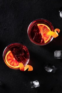 Negroni cocktails with orange rind, shot from the top with ice cubes on a black background, with