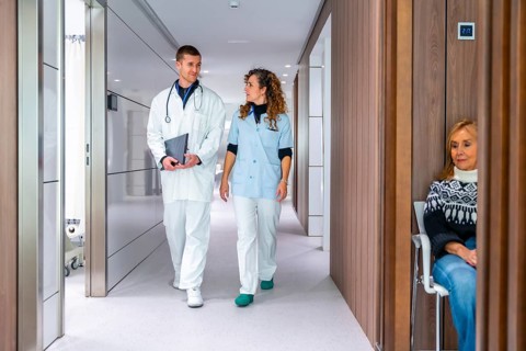 Medical colleagues walking and talking along the corridor of an hospital to the waiting room
