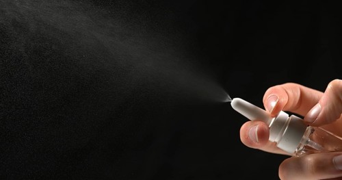 Hand of Woman and Nasal spray against Black Background