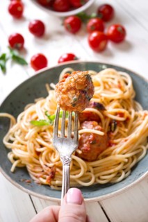Close-up of delicious meatball on a fork. Spaghetti with meatballs and tomato sauce on a plate.