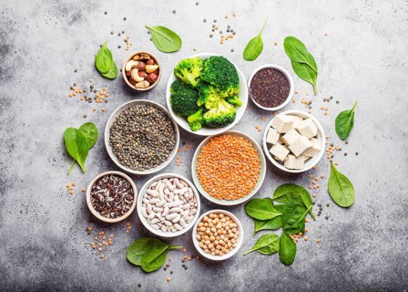 Top view of different vegan protein sources: beans, lentils, quinoa, tofu, vegetables, spinach,