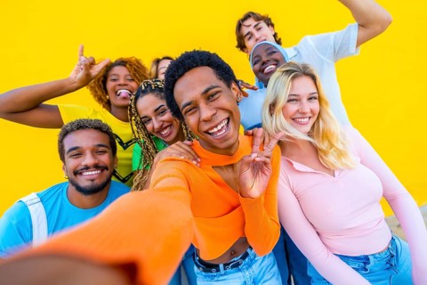 Transgender person gesturing peace while taking a selfie with multi-ethnic friends