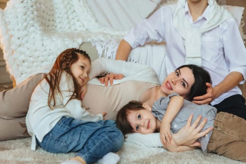 View from above of big family with two kids expecting new baby, waiting for third child. Pregnant