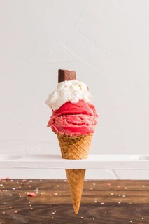 Red frozen ice scoop with with whipped cream chocolate cone