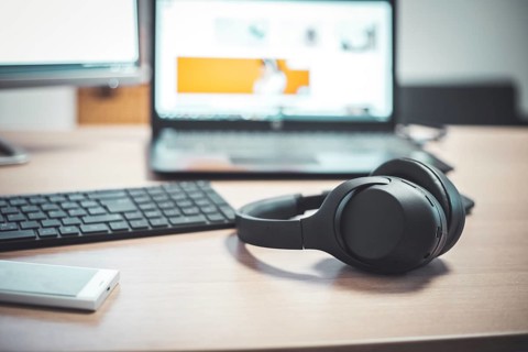 Wireless black headphones, mouse and keyboard on wooden desk