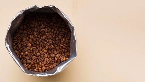 Black coffee beans beige background with copy space