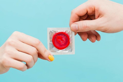People holding red condom