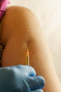 Close-up of a woman's arm getting a vaccination in blue latex gloves