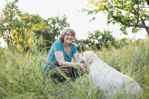 Elderly grayhaired woman with her lovely dog in the park. Portrait of a smiling senior female