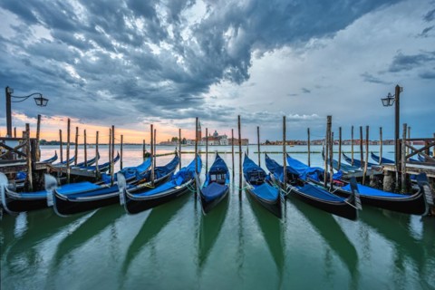 Gondolas in St Mark's Square in Venice, Italy, in front of a dramatic sunrise, Europe