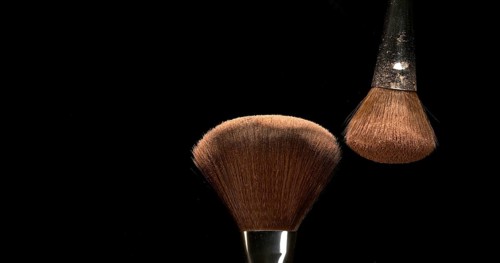 Make-up Brush spreading blush powder on black background
