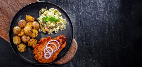 Chicken cutlet coated with breadcrumbs served with potatoes and cabbage