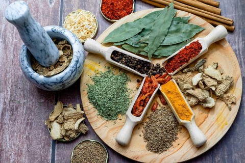 Different types of spices in wooden spoons on a wooden disk ginger, cayenne, pepper, cinnamon,