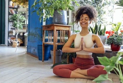 Young adult happy fit slim healthy African American ethnic woman wearing sportswear sitting in yoga