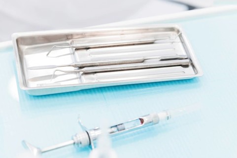 Close-up of a staminological instrument next to a metal syringe. Dental equipment. Dental hygiene