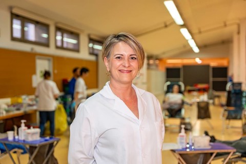 Portrait of a happy female blonde adult doctor in white lab coat in a blood donation center