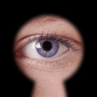 close-up of human female blue eye looking through keyhole
