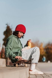 Side view teenager having lunch park skateboard