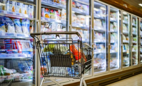 A shopping cart with grocery products in a supermarket