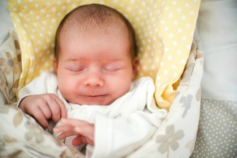 Cute newborn baby sleeping in swaddle wrap with smile on her face. Newborn theme