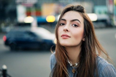 Close up young beautiful woman portrait posing in the city street in summer