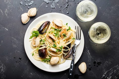 Spaghetti vongole, Italian seafood pasta with clams and mussels, in plate with herbs and two
