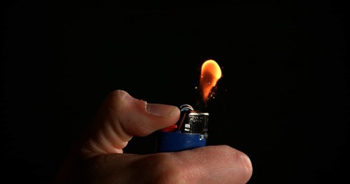 Lighter in Hand with Flame against Black background