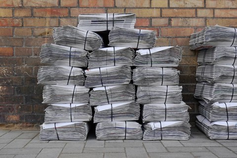 stacked and bundled tabloid newspapers on sidewalk