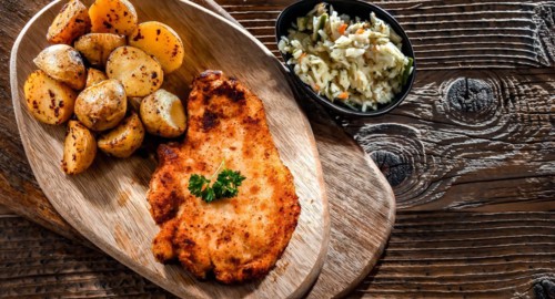 Chicken cutlet coated with breadcrumbs served with potatoes and cabbage