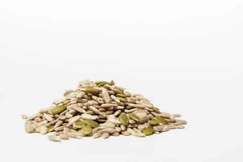 Pile of peeled pumpkin and sunflower seeds isolated on white background and copy space