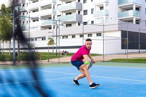 Man playing pickleball game, hitting pickleball ball with paddle, outdoor sport leisure activity