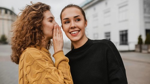Portrait teenager whispering her friends ear