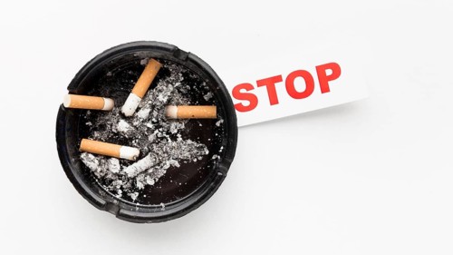 Ashtray with smoked cigarettes stop habit message