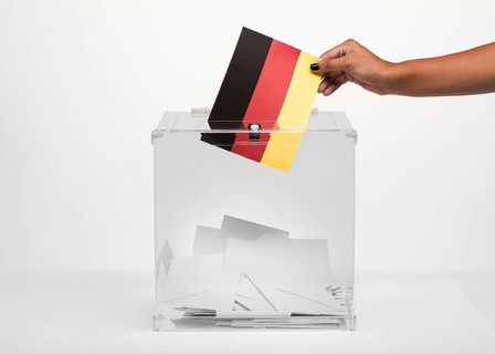 Person putting germany flag card into ballot box