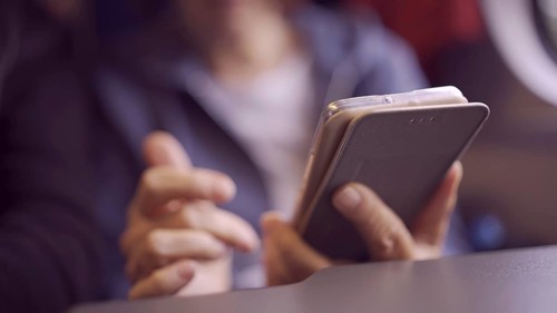 Close-up of the hands of an elderly woman sitting in a train carriageriage and using a smartphone