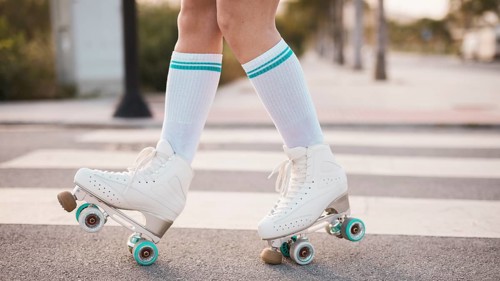Low section woman wearing vintage roller skate walking road. High resolution photo