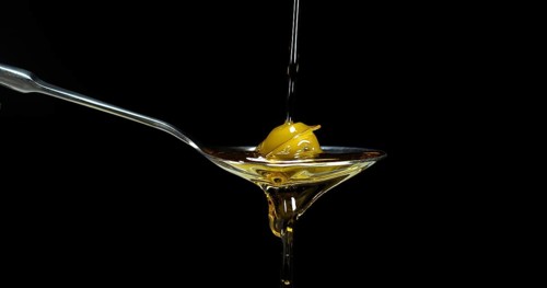 Green Olive, Olea europaea, Falling in a Spoon against Black Background