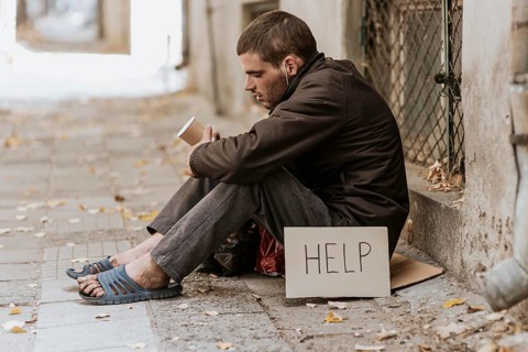Homeless man street with cup help sign