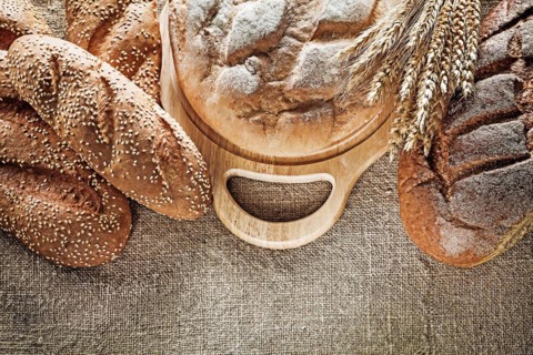 Black bread breadstick cutting board wheat ears on hessian background