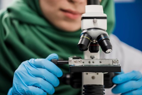 Female scientist with hijab working lab with microscope