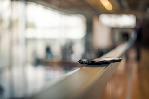 A smartphone lies on a railing