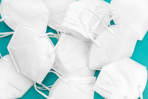 Group of used KN95 face mask on turquoise table. Coronavirus Covid-19 disposable masks wasting