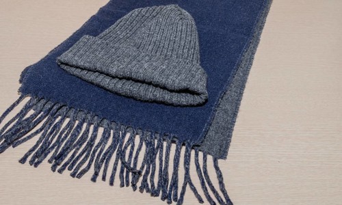 Gray knit cap laying on blue scarf on wood grain background, South Korea, South Korea, Asia